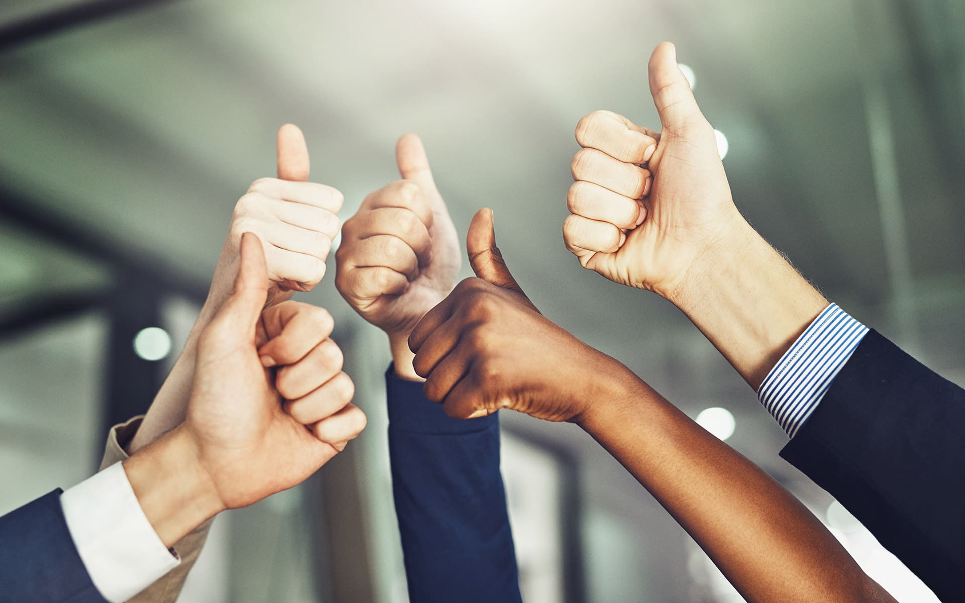 Fünf nach oben gestreckte Hände, die den Daumen hoch zeigen.